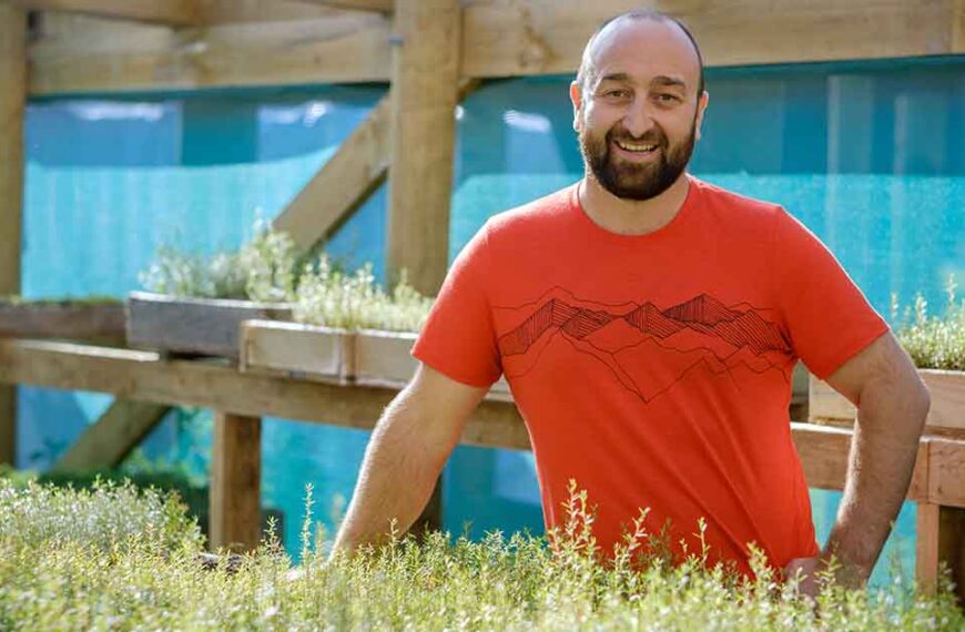 Adam Thompson stands in front of some seedlings in a nursery.